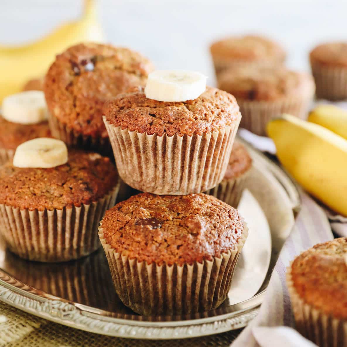 almond flour banana muffins on a silver platter with sliced banana.