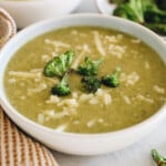 potato broccoli cheddar soup in a white bowl with roasted broccoli and shredded white cheddar cheese.