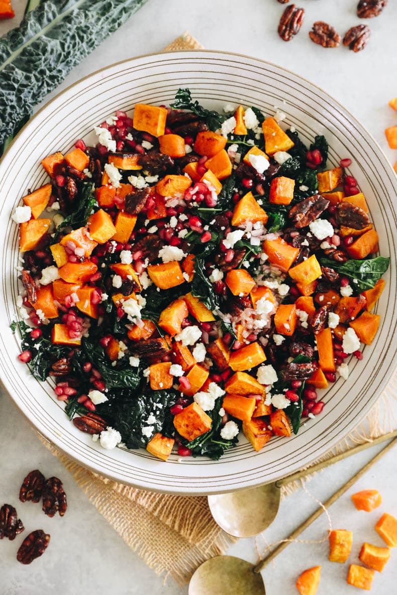 kale fall salad topped with roasted butternut squash, pomegranate seeds, candied pecans and feta cheese.