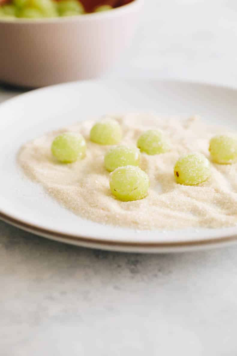 green grapes rolled in sugar on a white plate.