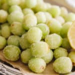 candy grapes with lemon juice and sugar on a parchment lined silver platter.