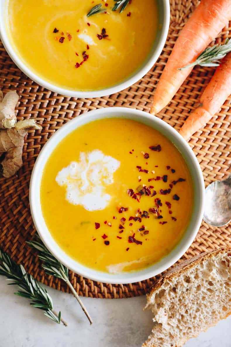 carrot soup in a white bowl with coconut milk and red pepper flakes.