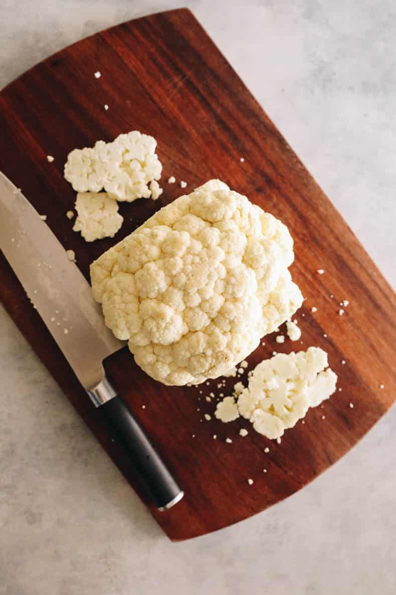 cauliflower cut into sliced steaks on a cutting board.