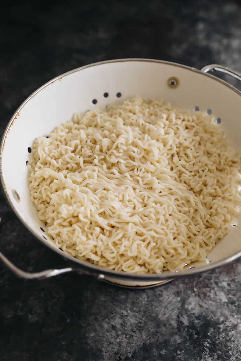 chow mein noodles cooked and drained in a white colander.