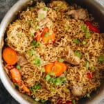 chicken chow mein cooked in a wok with carrots, green onions and cabbage.