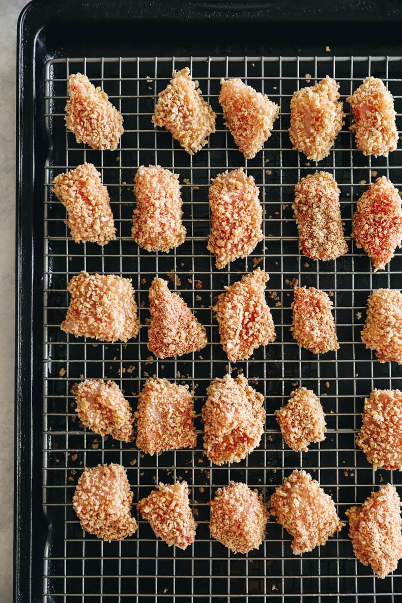 homemade chicken nuggets on a wire rack before baking.