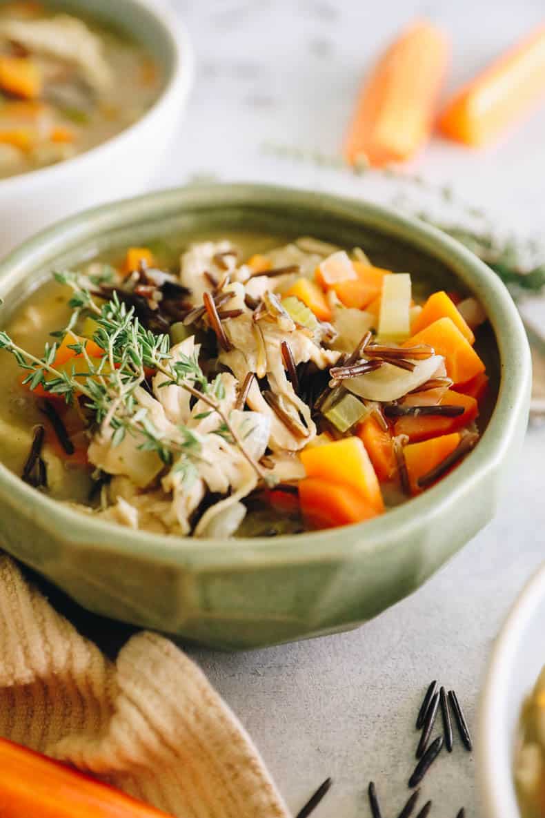 chicken wild rice soup in a green bowl topped with fresh thyme.