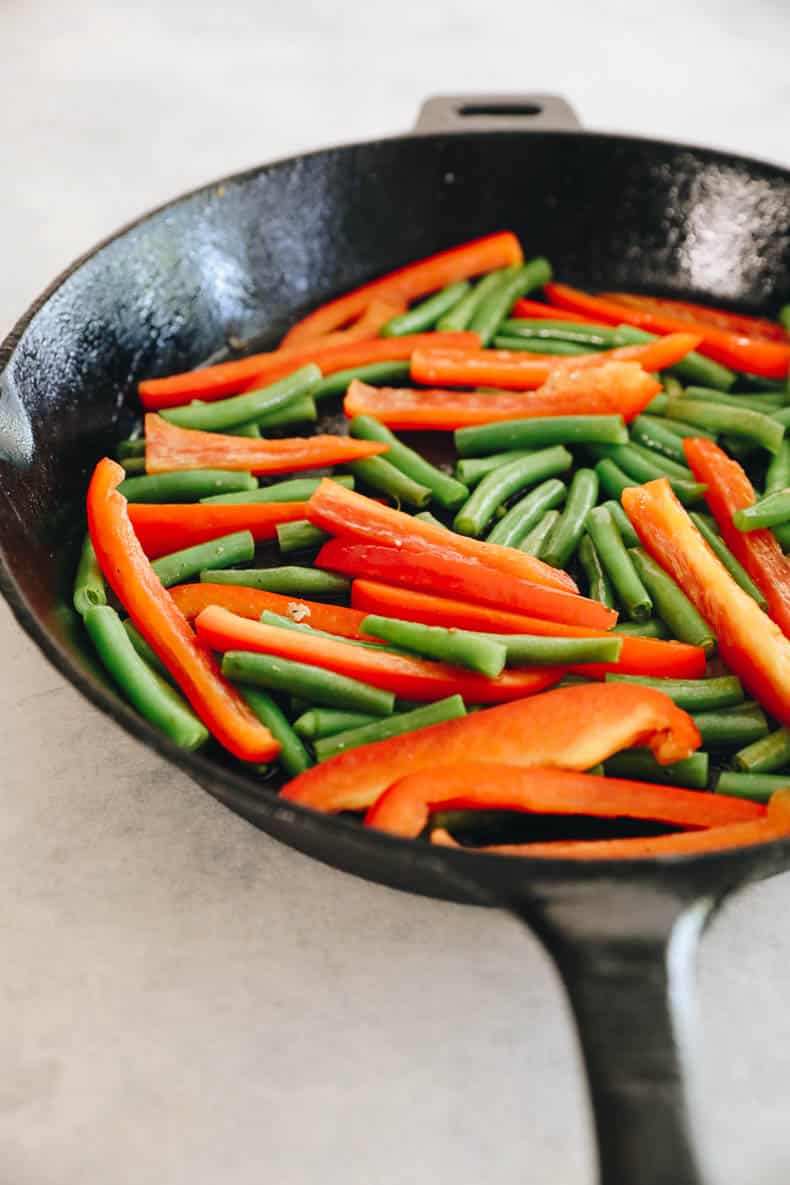 cooked bell pepper and green beans in a cast iron