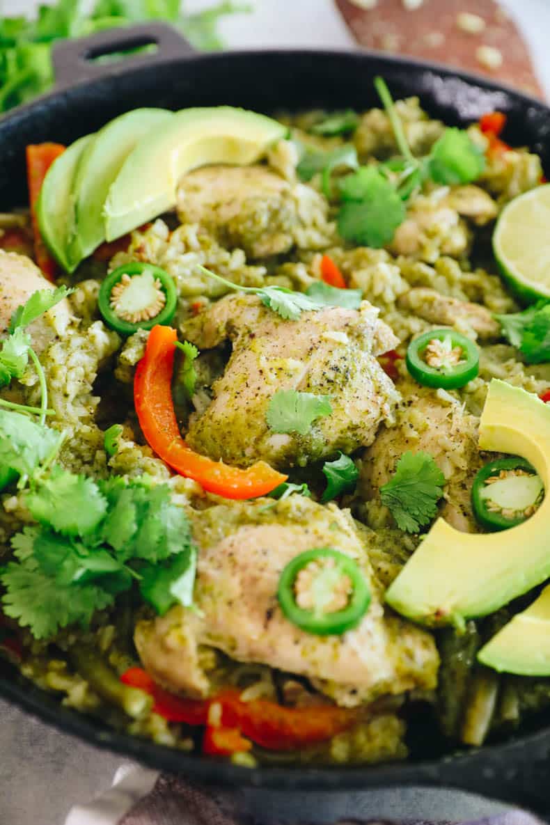 close-up of a cooke chicken thigh with rice and veggies in a cast iron dish.