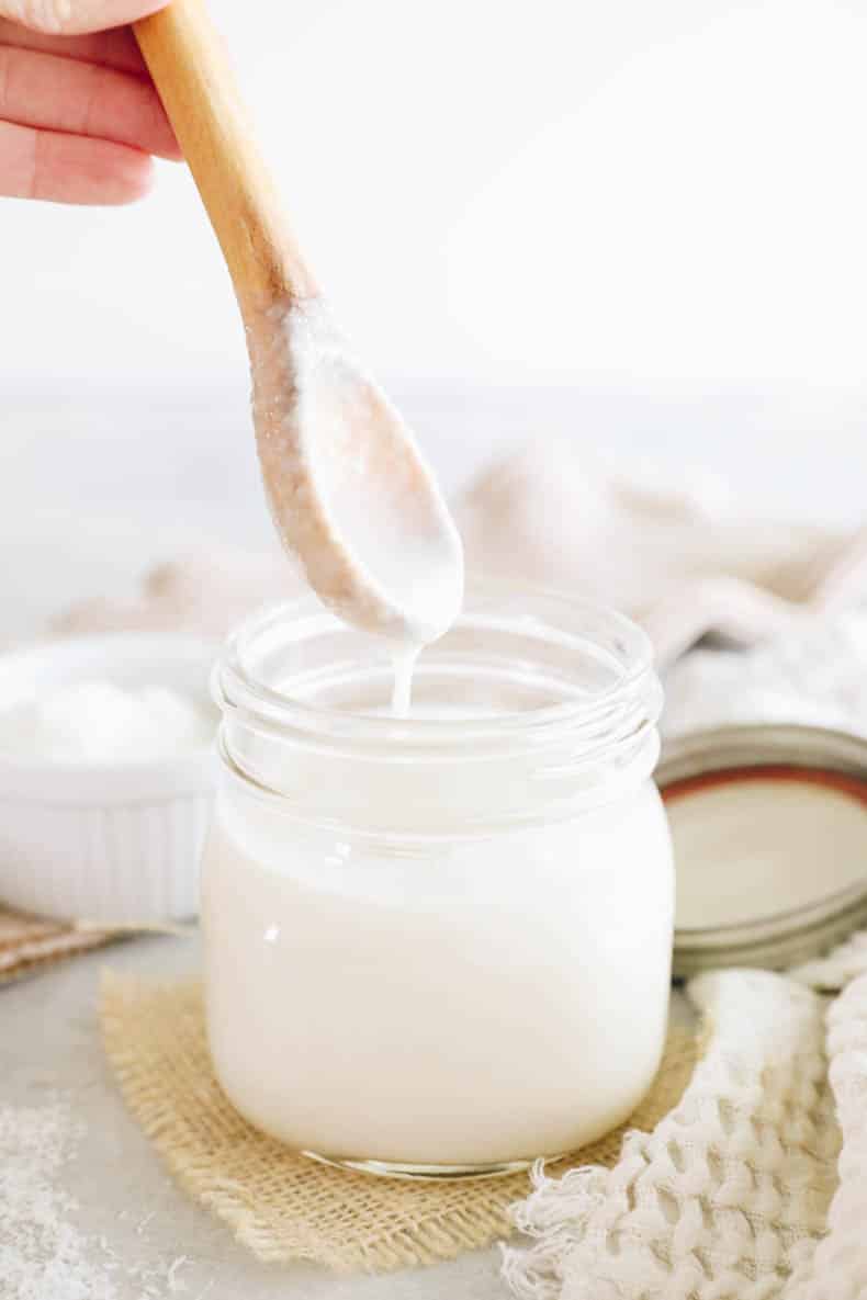 Drippy coconut butter in a mason jar with a wooden spoon.