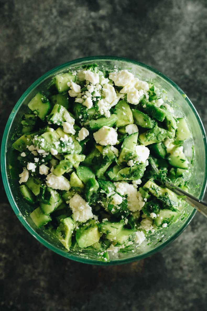 avocado salsa in a glass bowl with feta and cucumbers