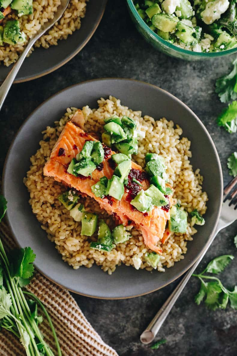 a blue plate with brown rice, baked salmon and avocado salsa.