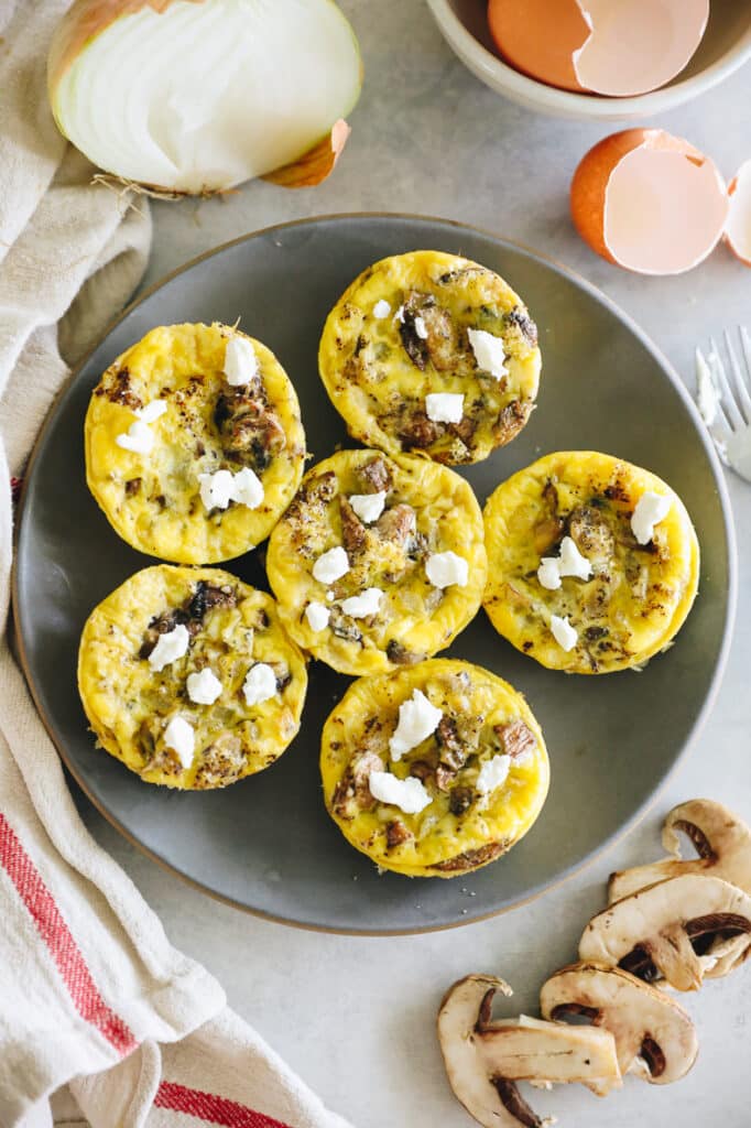 Overhead shot of a plate of egg muffins topped with goat cheese.