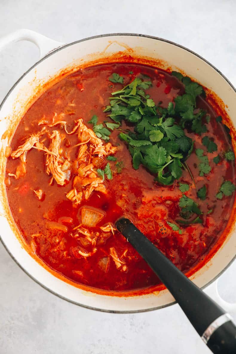 cilantro and shredded chicken in a big dutch oven of enchilada soup.