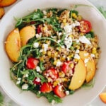 overhead image of farro salad with peaches, feta, tomatoes and arugula.