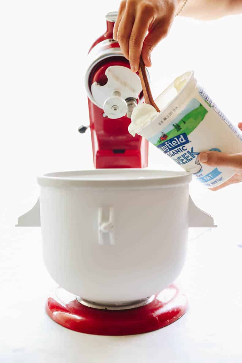 yogurt being added to a frozen yogurt machine.