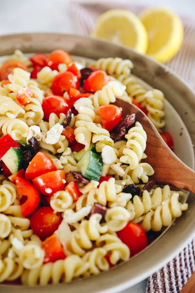 A wooden spoon scooping up pasta salad.