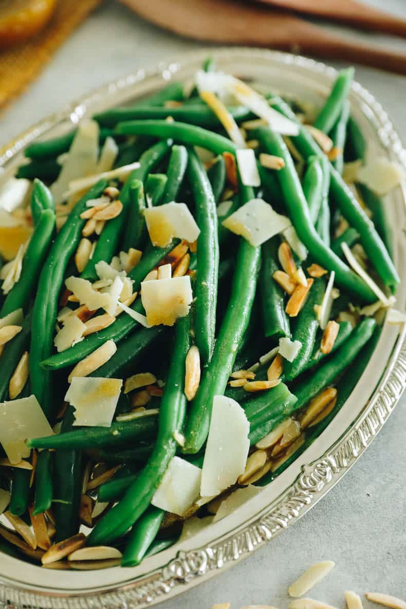 green bean salad on a silver plate topped with parmesan and almonds.