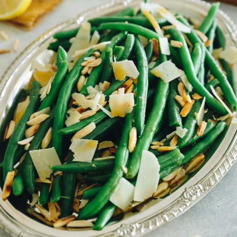 green bean salad with shaved parmesan and toasted almonds on a silver platter.