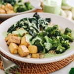 green goddess bowls in a white shallow bowl with broccoli, tofu, kale and green goddess dressing.