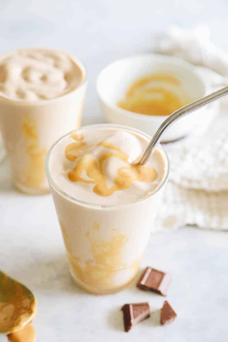 healthy chocolate peanut butter smoothie in a clear glass with a straw.