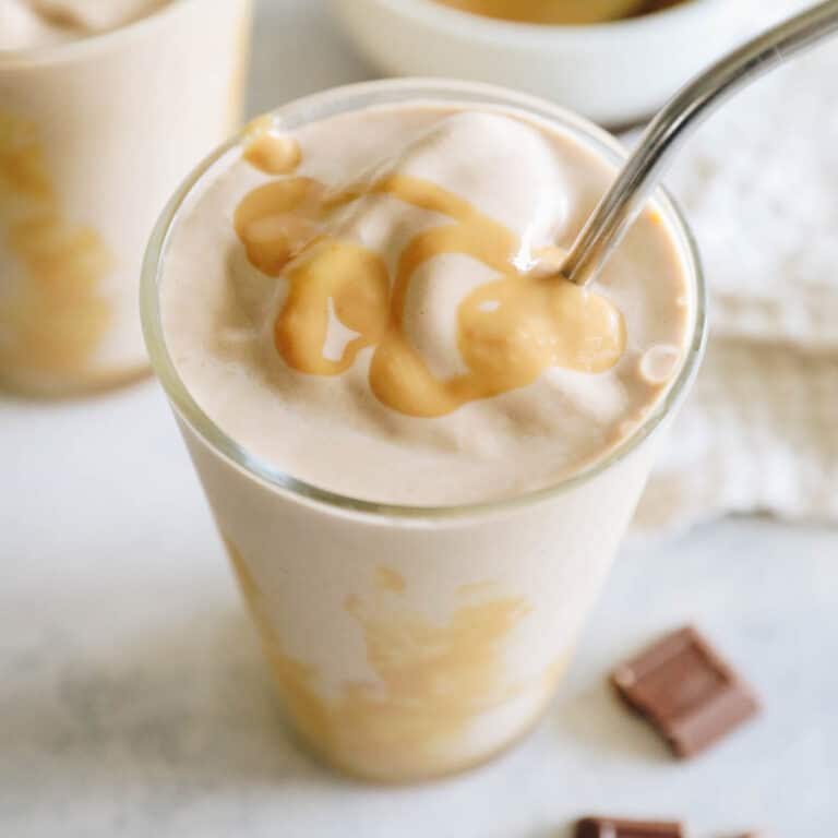 overhead image of a thick chocolate peanut butter smoothie with drizzled peanut butter and a metal straw.