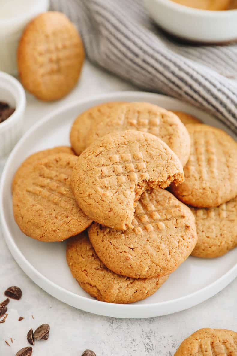 healthy peanut butter cookies stacked on top of each other on a white plate.