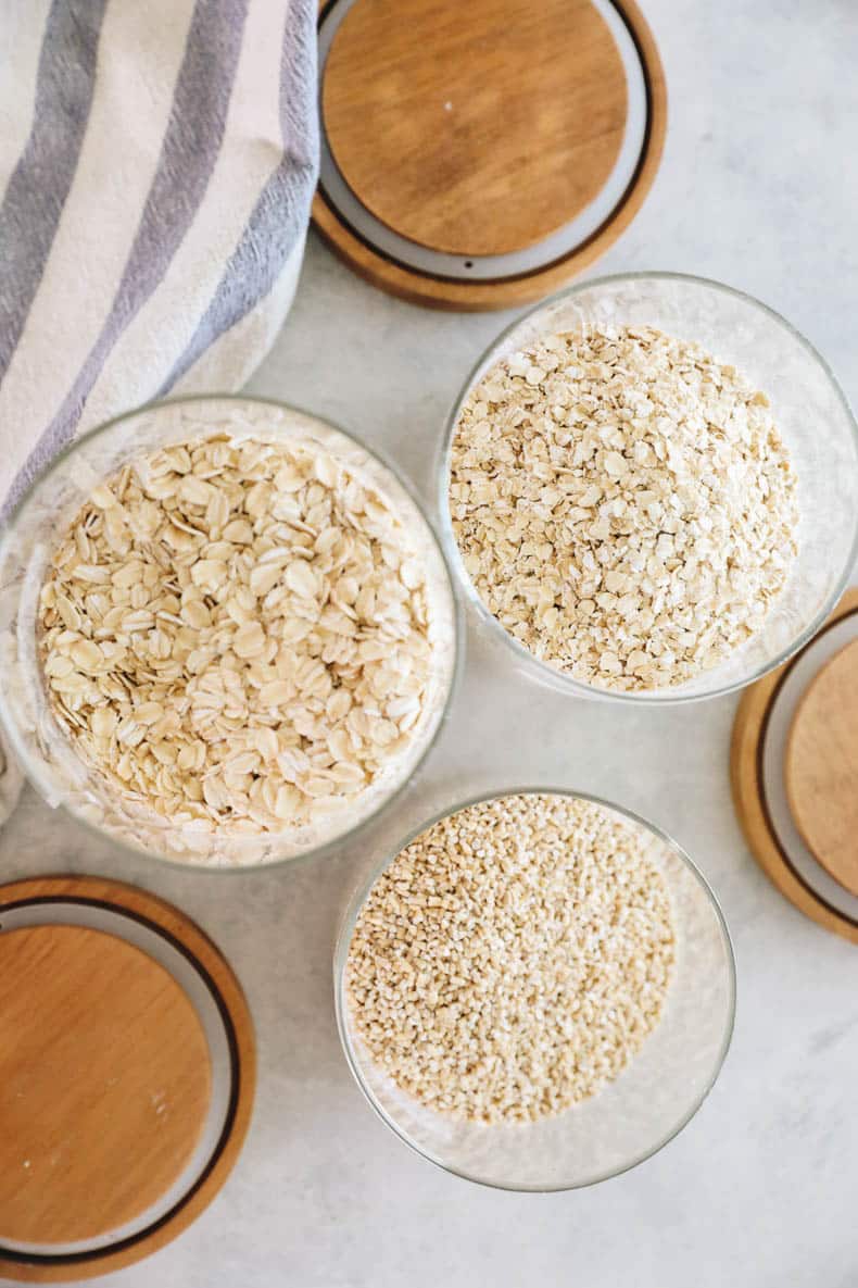 3 glass jars with different types of oats. One with regular rolled oats, one with steel-cut oats and one with quick cook oats.