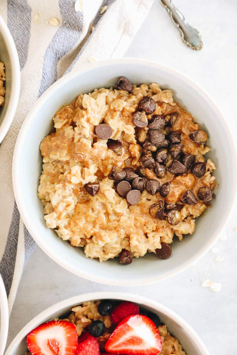 A bowl of oatmeal topped with chocolate chips and peanut butter.