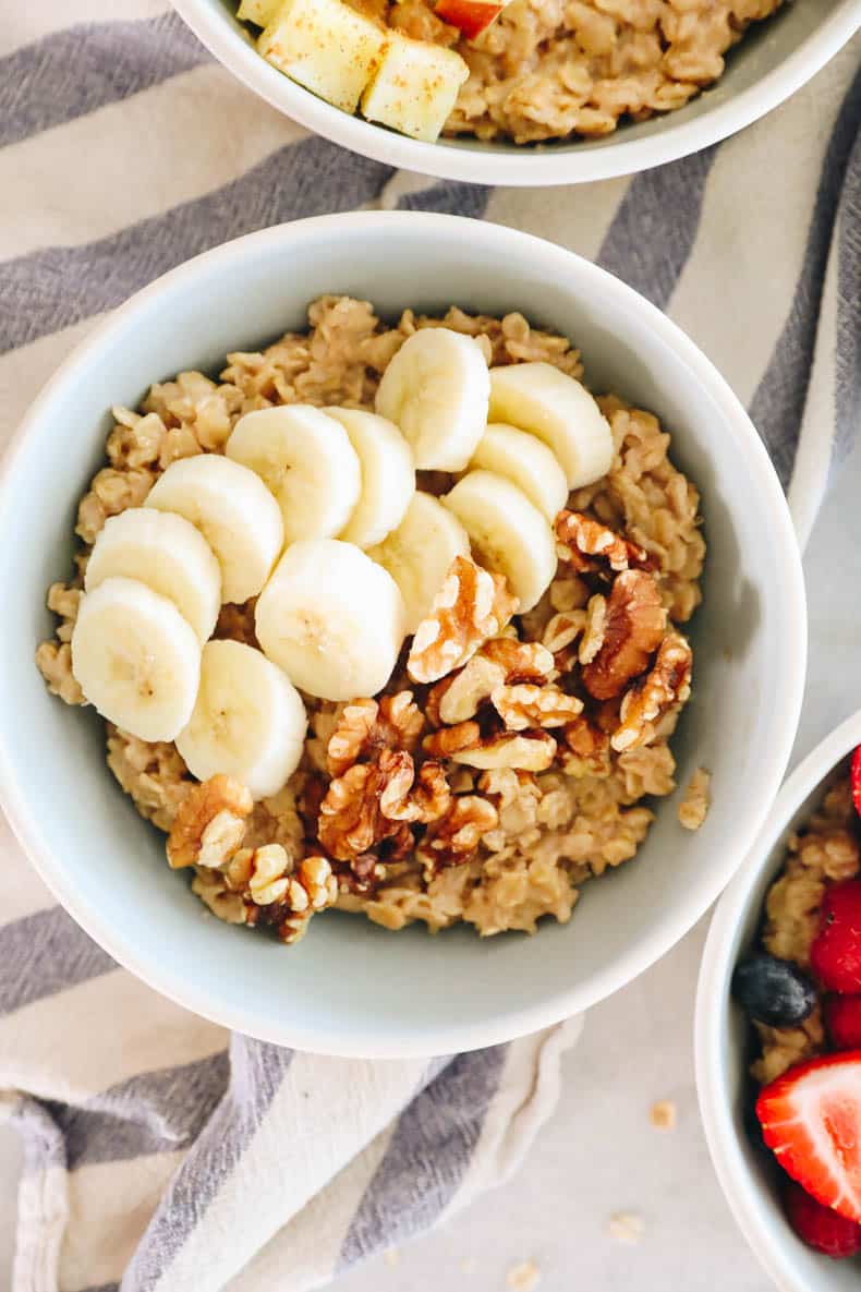 A bowl of oatmeal topped with banana and walnuts.