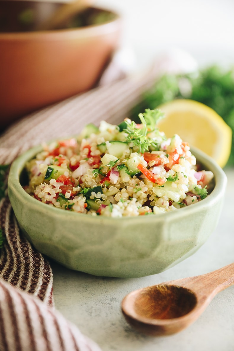 israeli salad veggies mixed with quinoa in a green bowl