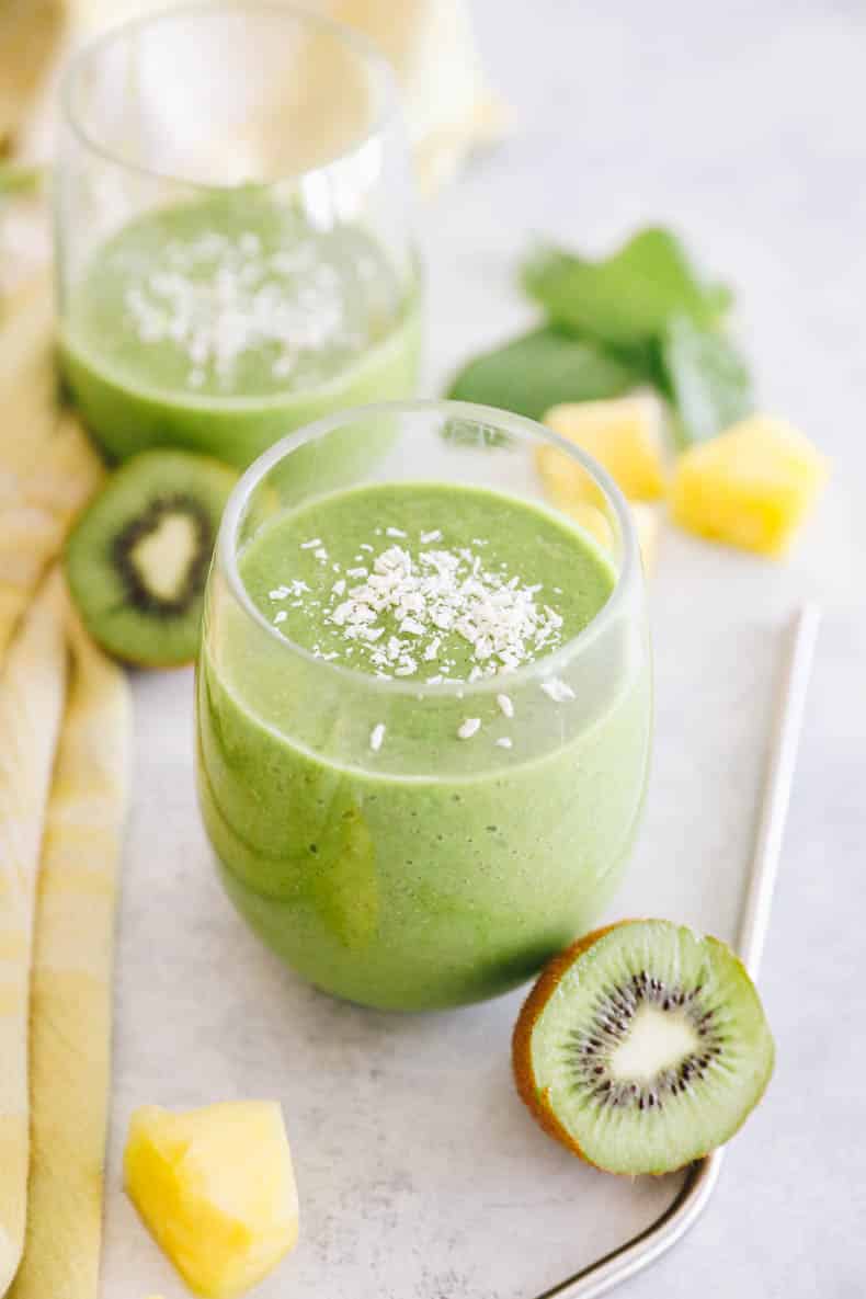 two cups with kiwi smoothie on a white table.