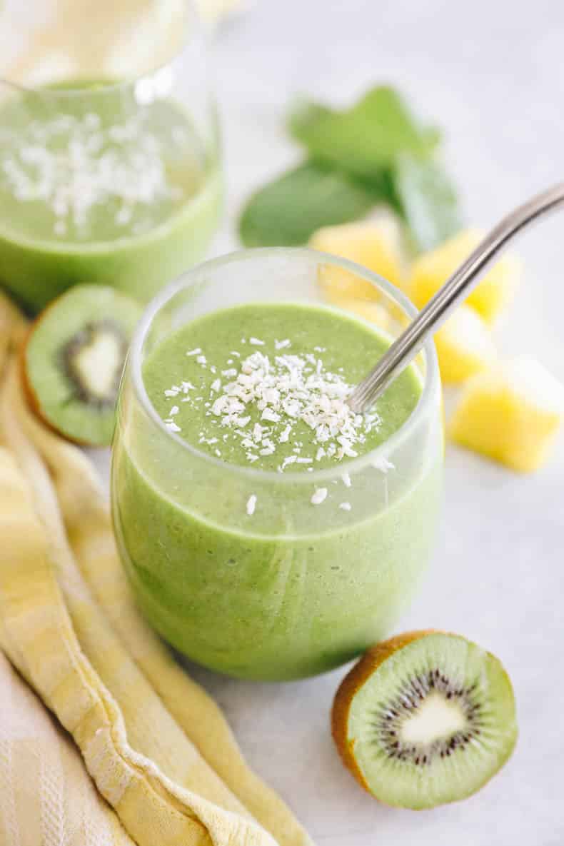 kiwi smoothie in a glass with a metal straw and sprinkled with coconut.