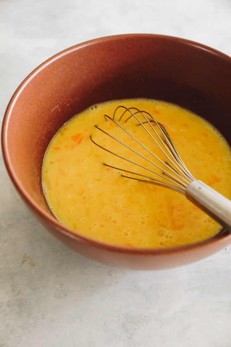 whisked eggs and milk in a brown bowl.