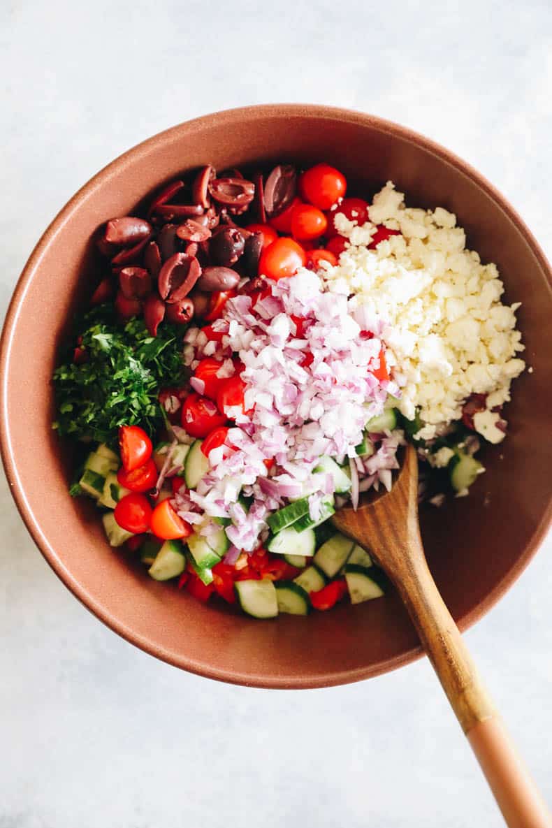 ingredients for mediterranean chickpea salad in a large brown bowl.