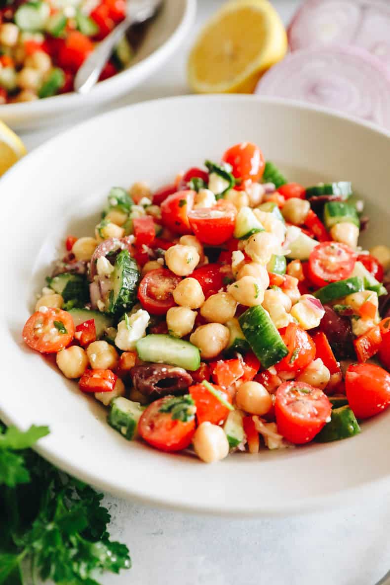 upclose image of mediterranean chickpea salad in a white shallow bowl.