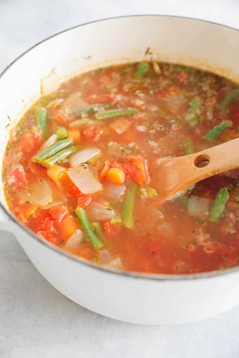 Large dutch oven with tomato-based soup.