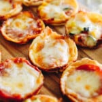 mini tortilla pizza bites on a brown cutting board stuffed with cheese and pepperonis