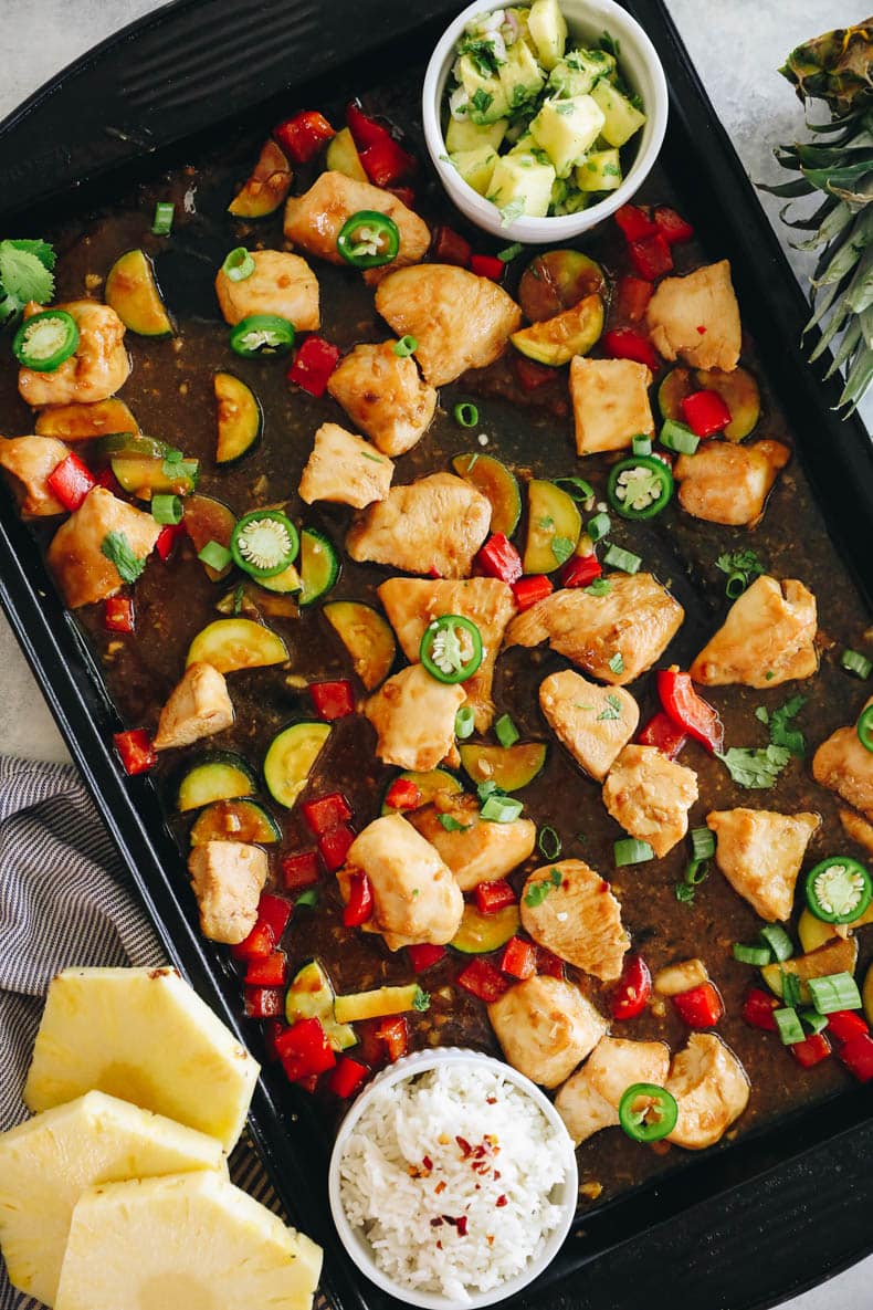 Overhead of a sheet pan with pineapple chicken and veggies.