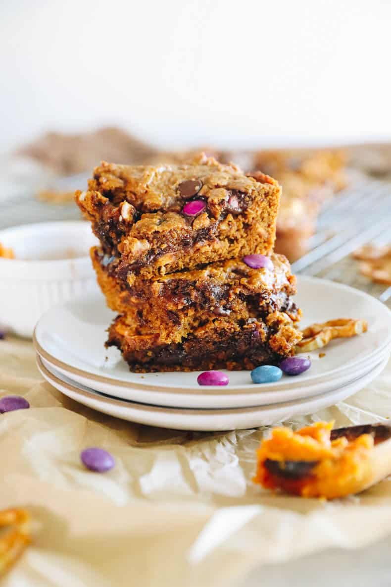 3 pumpkin spice monster cookie bars stacked on a white plate.