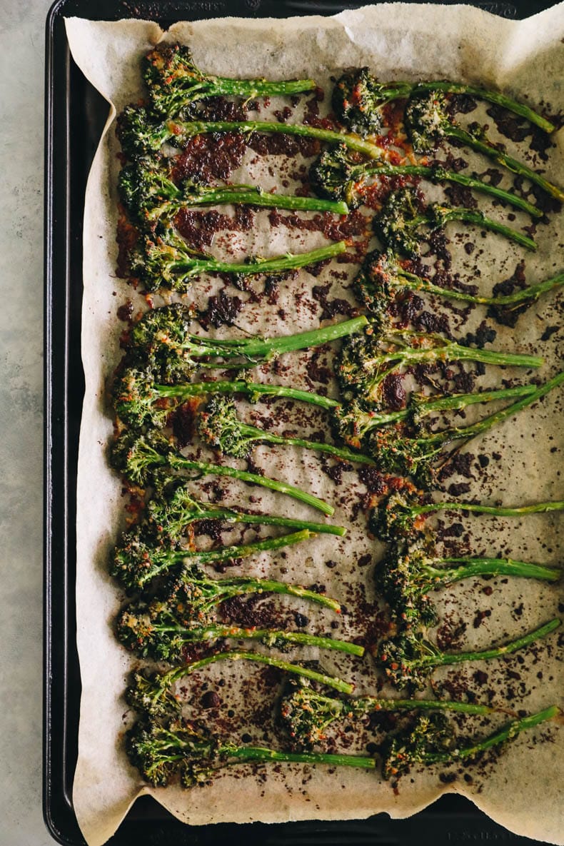 Roasted broccolini on a sheet pan sprinkled with parmesan.