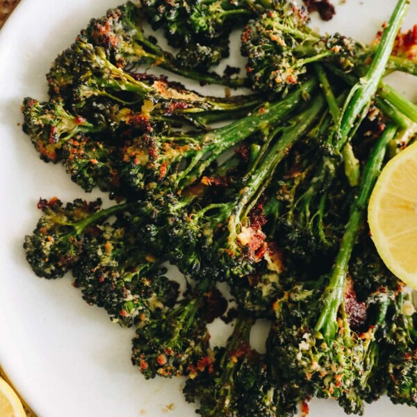 roasted broccolini with lemon on a white plate with parmesan.