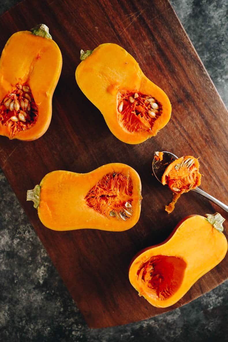 raw honeynut squashes cut open on a cutting board.