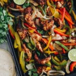 sheet pan fajitas on a roasting pan with bell peppers and onions