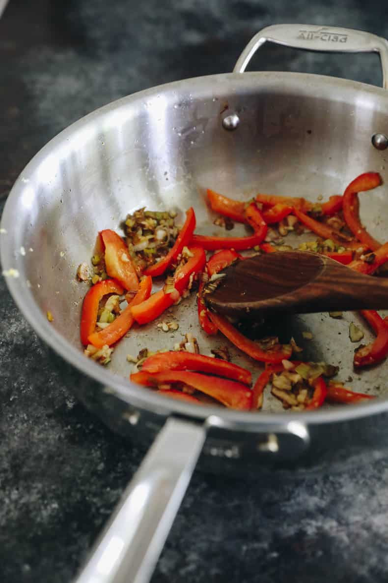 Cooked scallions, garlic, ginger and red bell pepper in a wok.