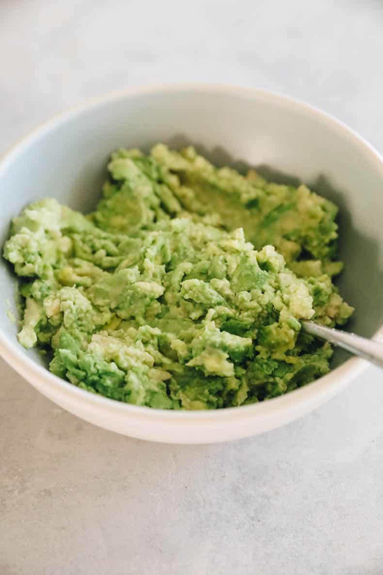 Avocado mash in a blue and white bowl.