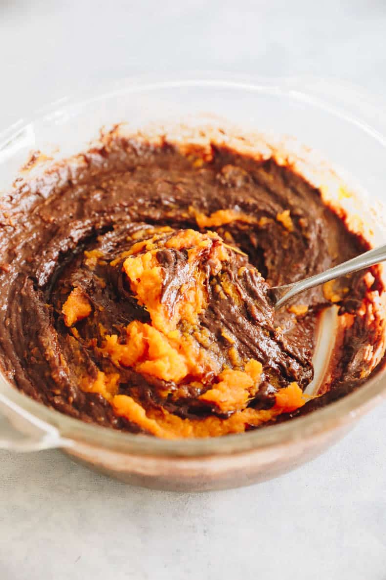 sweet potato brownie batter in a clear glass bowl.