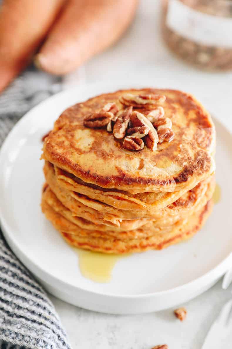 stack of sweet potato pancakes that are orange on a white plate.