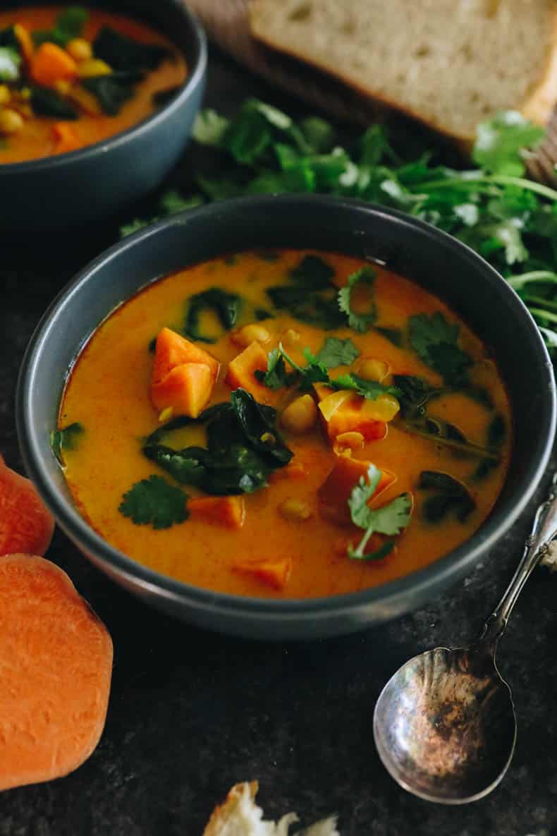 curried sweet potato soup in a blue bowl with garbanzo beans, swiss chard and cilantro.