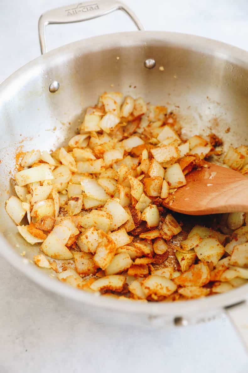 onions and garlic and spices cooking in a pot.